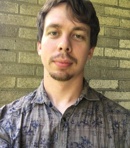 Photo of Joshua Lew McDermott in front of a brick wall